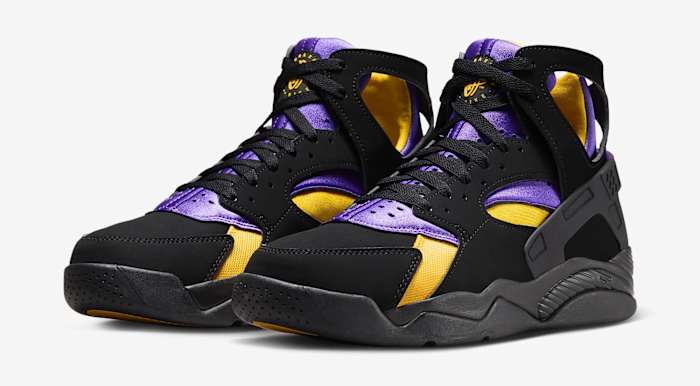 Side view of black, purple, and gold Nike Huarache shoes.